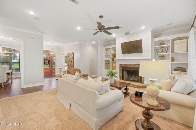 living room with a fireplace, crown molding, ceiling fan with notable chandelier, and hardwood / wood-style flooring