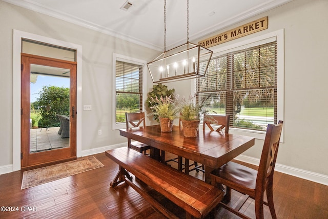 dining room with dark wood-type flooring, a chandelier, and crown molding