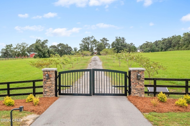 view of gate with a yard and a rural view