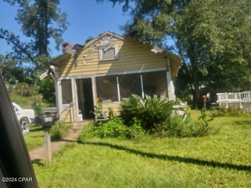 back of property with a sunroom and a yard