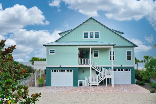 raised beach house featuring covered porch and a garage