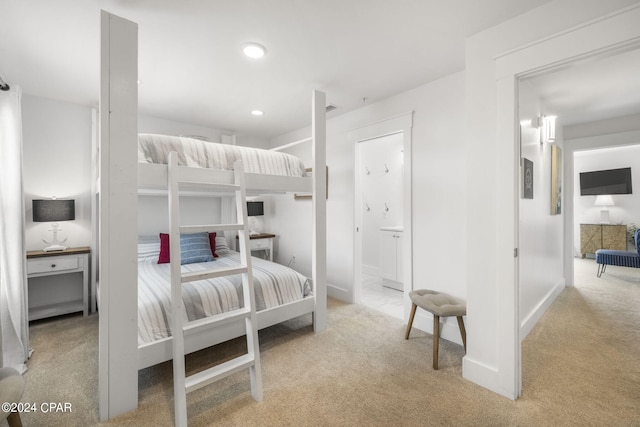 bedroom featuring ensuite bath and light carpet