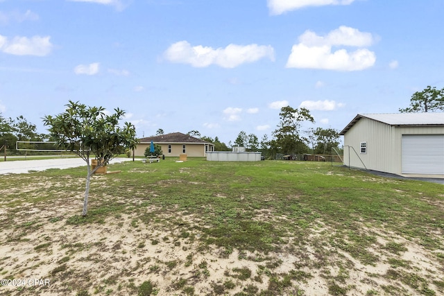 view of yard featuring a swimming pool, volleyball court, an outdoor structure, and a garage