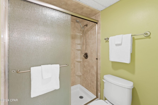 bathroom featuring toilet and a shower with shower door