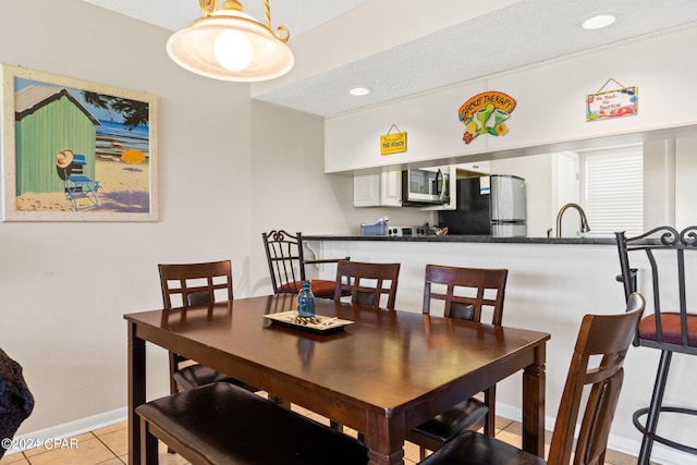 tiled dining room featuring a textured ceiling and sink