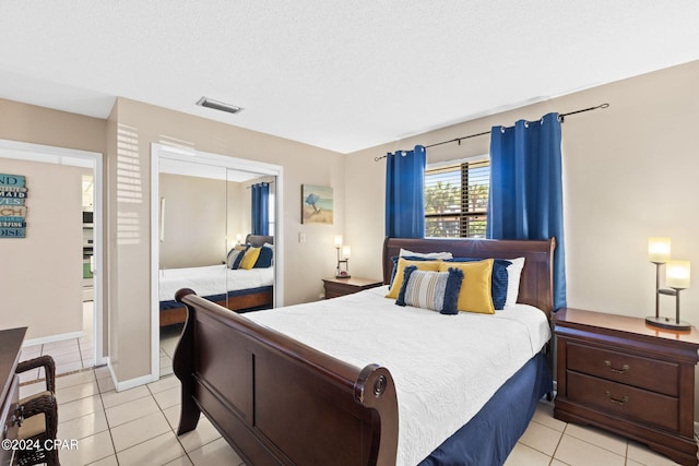 bedroom featuring a closet, a textured ceiling, and light tile patterned floors