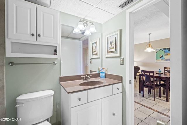 bathroom featuring vanity, a drop ceiling, toilet, and tile patterned floors