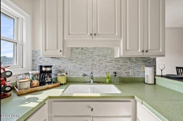 kitchen featuring decorative backsplash, sink, and white cabinetry