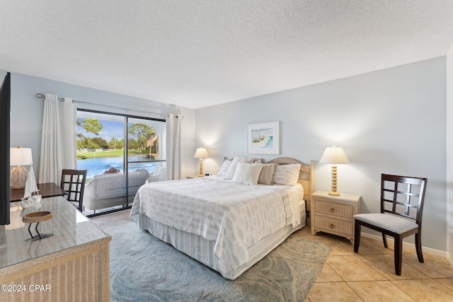 tiled bedroom with a textured ceiling and access to outside