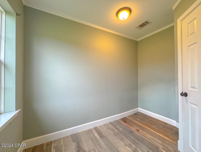 empty room featuring ornamental molding and hardwood / wood-style floors