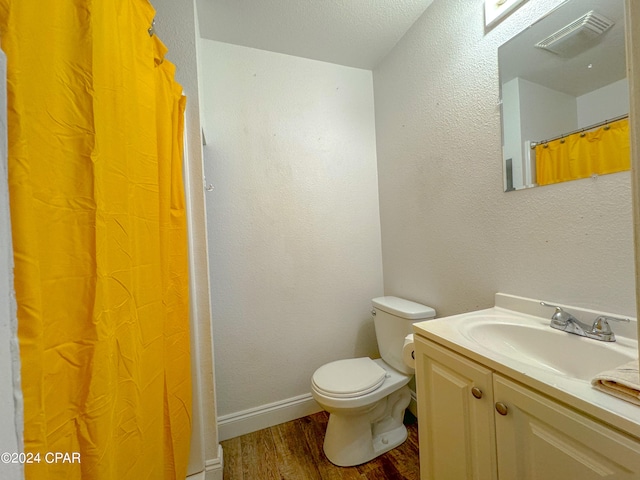 bathroom featuring a textured ceiling, wood-type flooring, vanity, and toilet