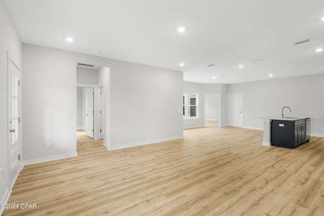 unfurnished living room with sink and light hardwood / wood-style floors