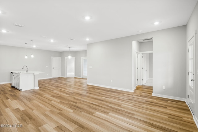 unfurnished living room with light hardwood / wood-style floors and sink