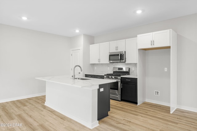 kitchen with white cabinetry, appliances with stainless steel finishes, sink, and a kitchen island with sink