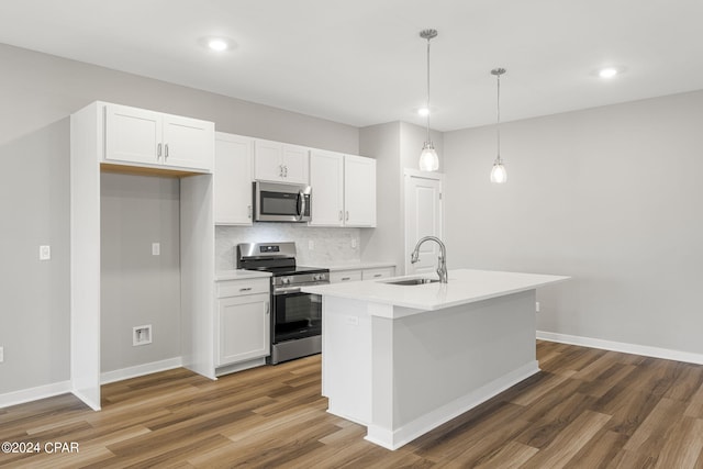 kitchen with white cabinets, an island with sink, appliances with stainless steel finishes, pendant lighting, and sink