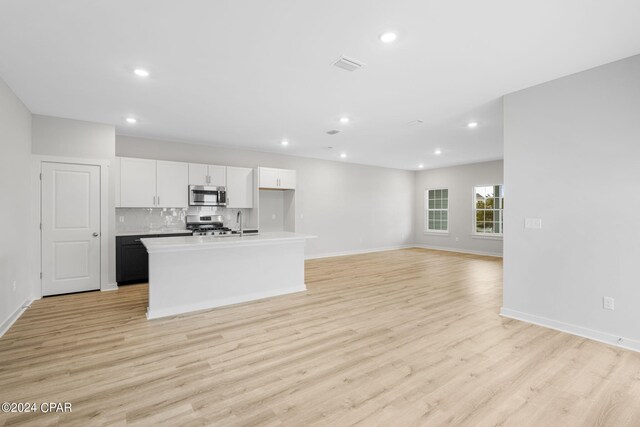 kitchen with appliances with stainless steel finishes, white cabinetry, a center island with sink, and light hardwood / wood-style floors