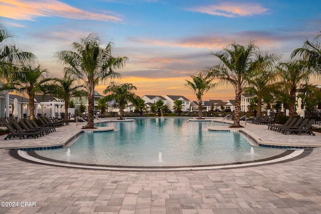 pool at dusk with a patio and pool water feature