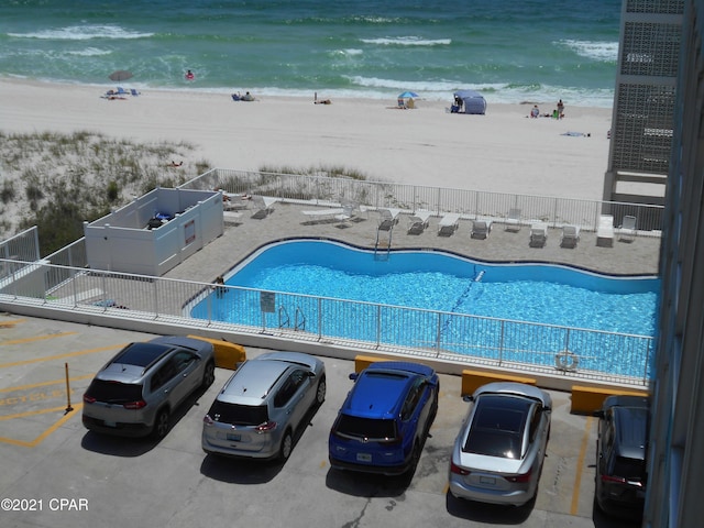 view of swimming pool with a view of the beach, a water view, and a patio area