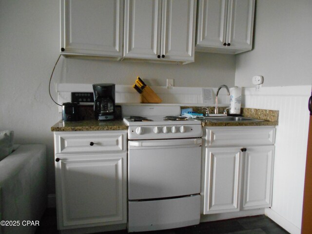 kitchen with dark stone counters, white range, sink, and white cabinets