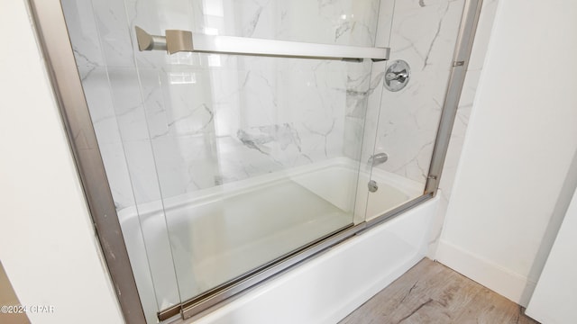 bathroom featuring hardwood / wood-style floors and combined bath / shower with glass door