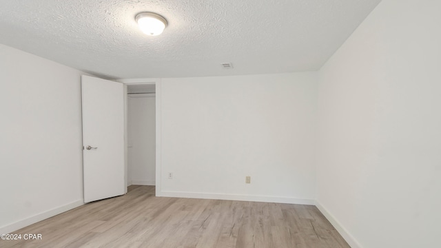 spare room with a textured ceiling and light hardwood / wood-style floors