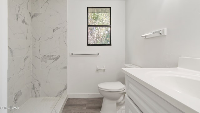 bathroom featuring vanity, hardwood / wood-style floors, toilet, and tiled shower