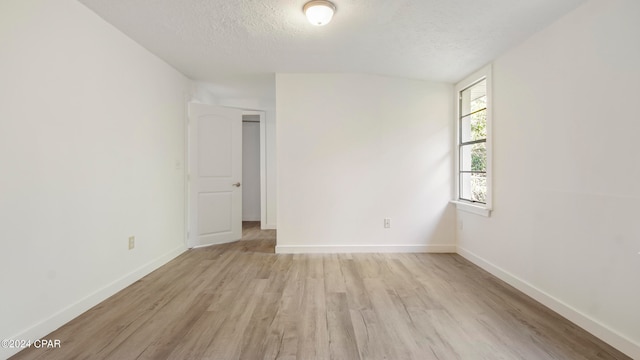 unfurnished room with a textured ceiling and light hardwood / wood-style floors