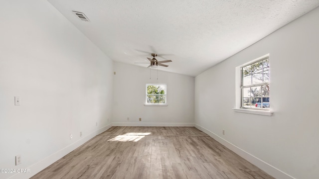 spare room with ceiling fan, light hardwood / wood-style floors, vaulted ceiling, and a wealth of natural light