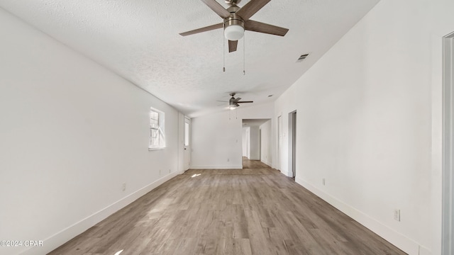 unfurnished room with ceiling fan, a textured ceiling, and light wood-type flooring