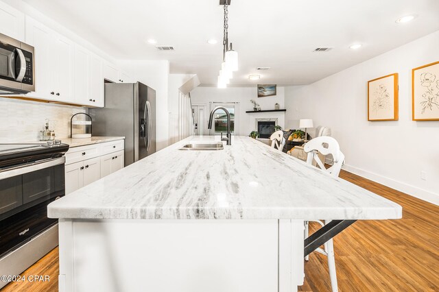 kitchen with a center island with sink, stainless steel appliances, sink, and a breakfast bar