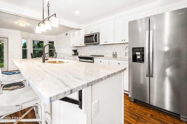 kitchen with appliances with stainless steel finishes, dark wood-type flooring, sink, and an island with sink