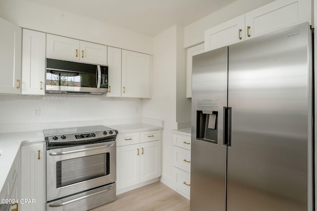 kitchen with white cabinets, backsplash, appliances with stainless steel finishes, and light wood-type flooring