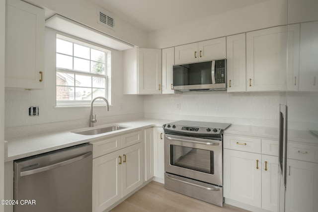 kitchen featuring white cabinetry, sink, light hardwood / wood-style flooring, and stainless steel appliances