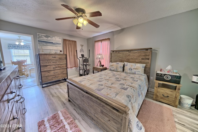 bedroom with light hardwood / wood-style flooring, a textured ceiling, and ceiling fan