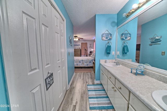 bathroom featuring vanity, ceiling fan, wood-type flooring, and a textured ceiling