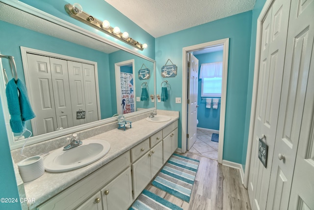 bathroom with a textured ceiling, walk in shower, wood-type flooring, toilet, and vanity