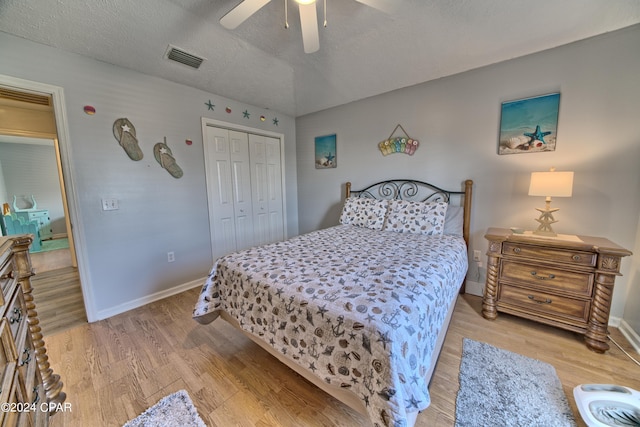 bedroom featuring light hardwood / wood-style floors, a closet, a textured ceiling, and ceiling fan