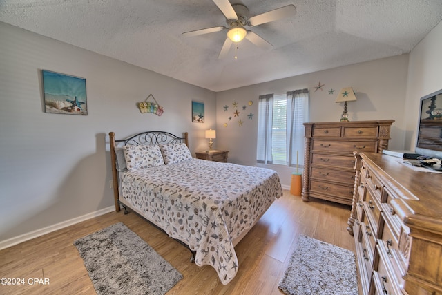 bedroom with light hardwood / wood-style flooring, a textured ceiling, and ceiling fan