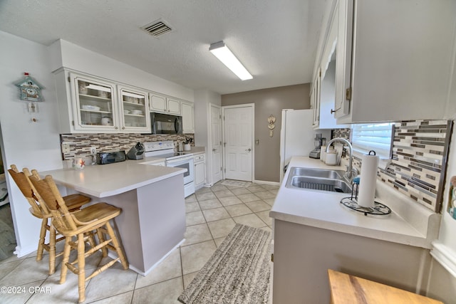 kitchen featuring kitchen peninsula, sink, a kitchen bar, white cabinetry, and white appliances