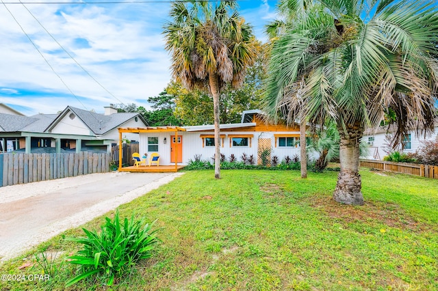 view of front of house with driveway, a front yard, and fence