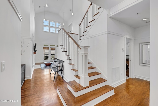 stairs featuring hardwood / wood-style floors and high vaulted ceiling