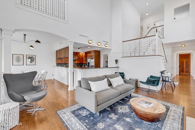 living room featuring a high ceiling, decorative columns, and light hardwood / wood-style floors