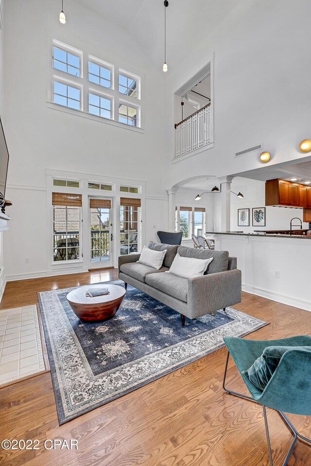 living room with wood-type flooring, ornate columns, and a high ceiling