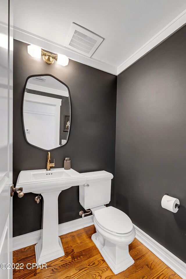 bathroom with ornamental molding, toilet, and hardwood / wood-style floors