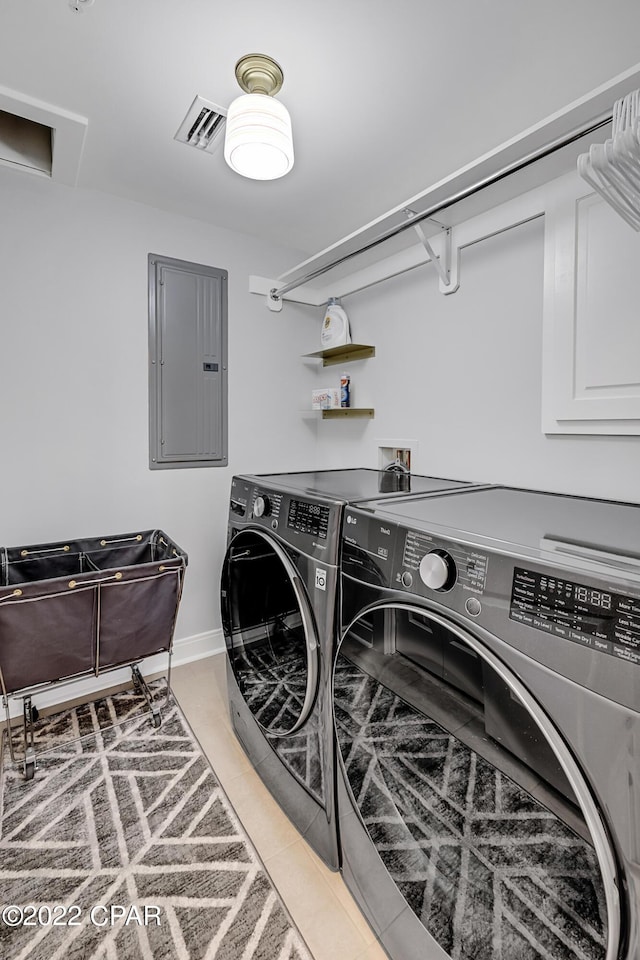 washroom featuring washer and dryer, tile patterned floors, and electric panel