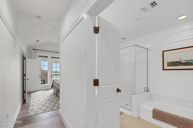 bathroom with lofted ceiling, wood-type flooring, and plus walk in shower