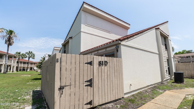 view of property exterior with a lawn and central AC unit