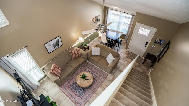 tiled living room with ceiling fan and a textured ceiling