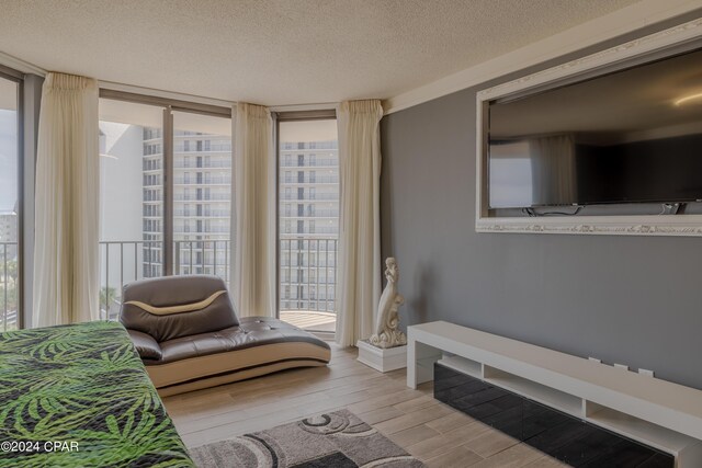 living room with a wall of windows, light hardwood / wood-style floors, and a textured ceiling