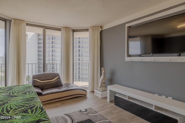 living area with a textured ceiling, a wall of windows, and wood finished floors